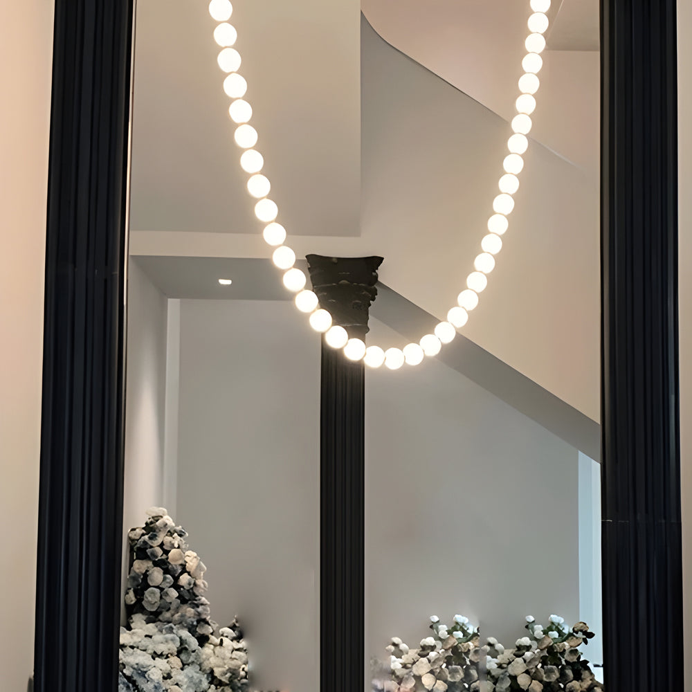 Pearl necklace light fixture with a decorative design, hanging near a fireplace.