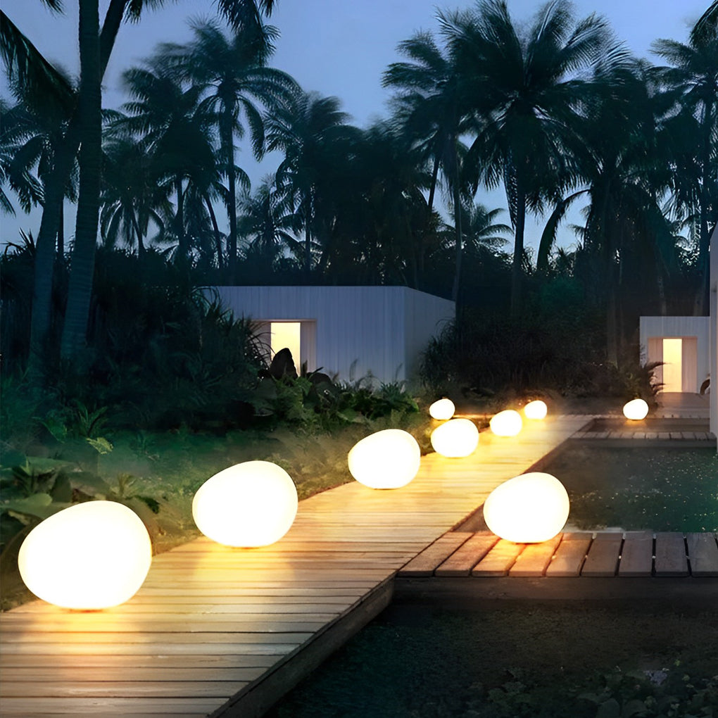 Pebble lights arranged along garden pathway with warm illumination.