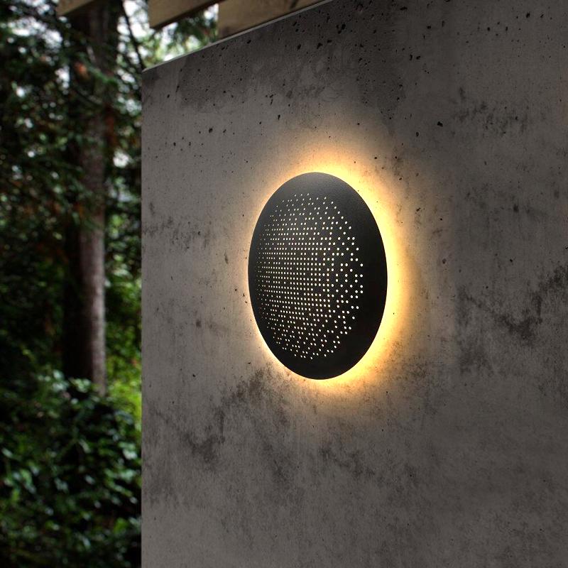 Perforated metal wall sconce close-up showing patterned light projection on wall.