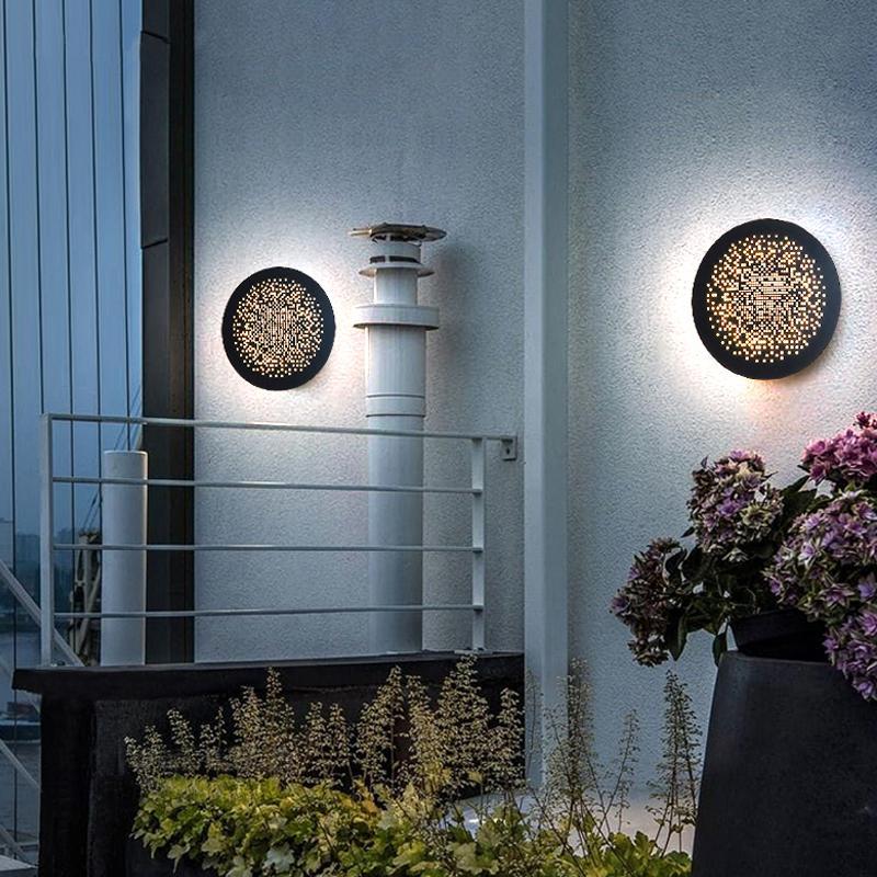 Perforated metal wall sconce mounted near an exterior staircase and railing.