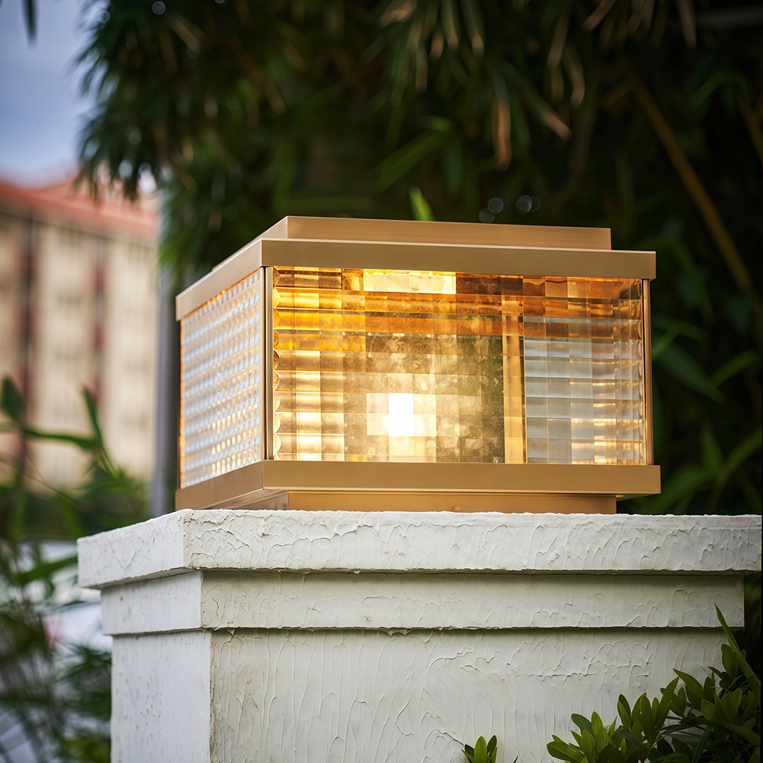 Pillar cap lights mounted on white stone column beside residential entrance with natural garden setting.