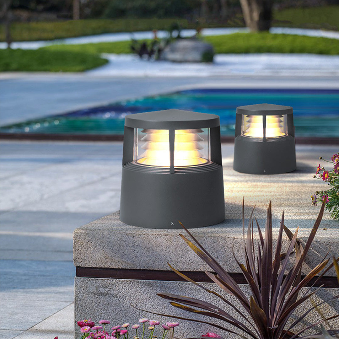 Two short garden lights illuminating walkway near pool and plants