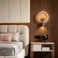 Modern reading light for bed wall mounted beside upholstered headboard with glowing circular LED halo.