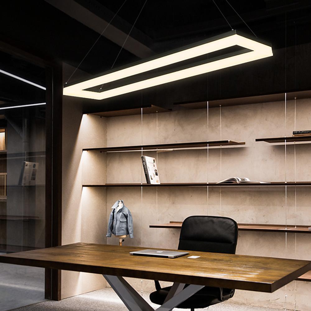 Linear rectangular pendant light illuminating workspace with wood shelving background.