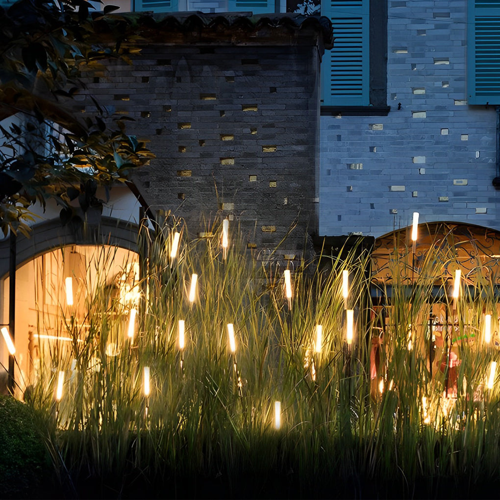 Reed lights creating ambient glow beside stone wall in outdoor setting.