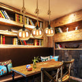 Multiple retro glass pendant lights creating atmospheric lighting in trendy cafe environment.