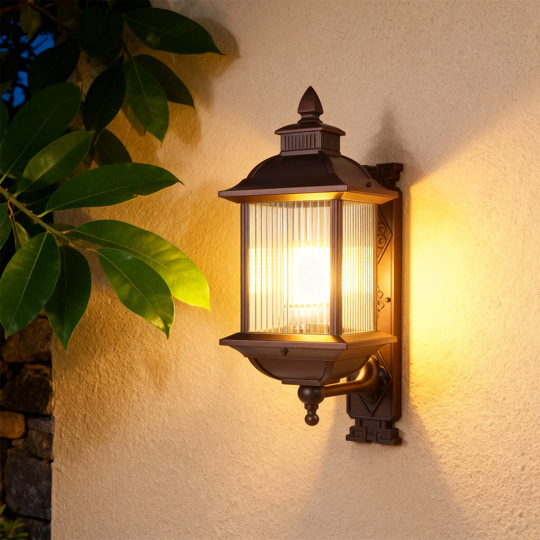 Retro outdoor wall light with Edison bulb illuminating textured yellow exterior wall at dusk
