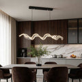 Ribbon pendant light with a modern wave design, hanging above a dining table in a contemporary kitchen.