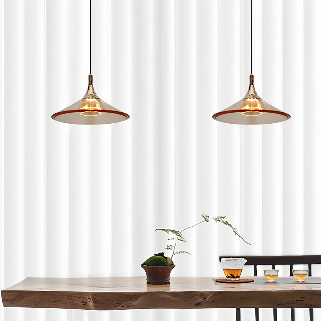 Dual rise and fall pendant lights with golden shades above rustic wooden dining table with white curtains