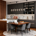 Stylish dining room illuminated by a round chandelier modern fixture with glowing glass rings.