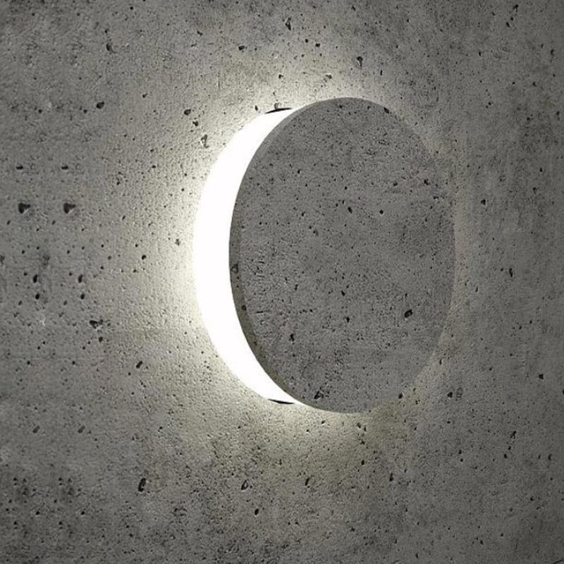 Round exterior wall lights with a minimalist design, mounted on a concrete wall.