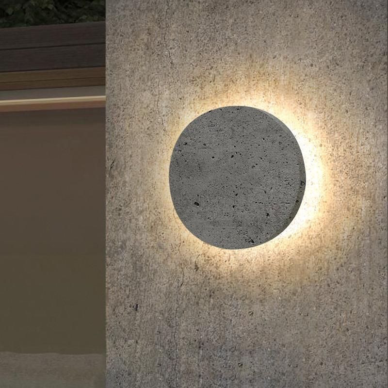 Round exterior wall lights with a sleek design, providing ambient lighting on a textured wall.