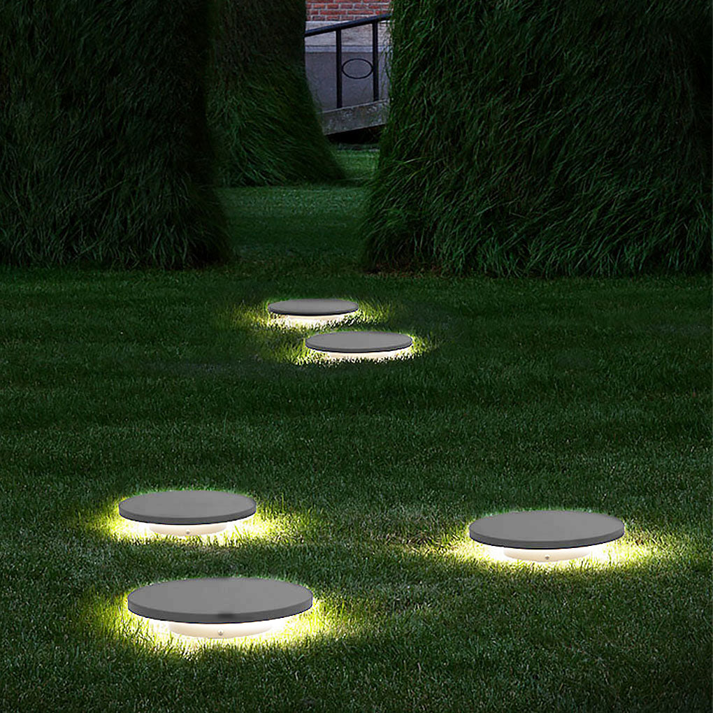 Round lawn lights evenly spaced on grass for nighttime landscape lighting