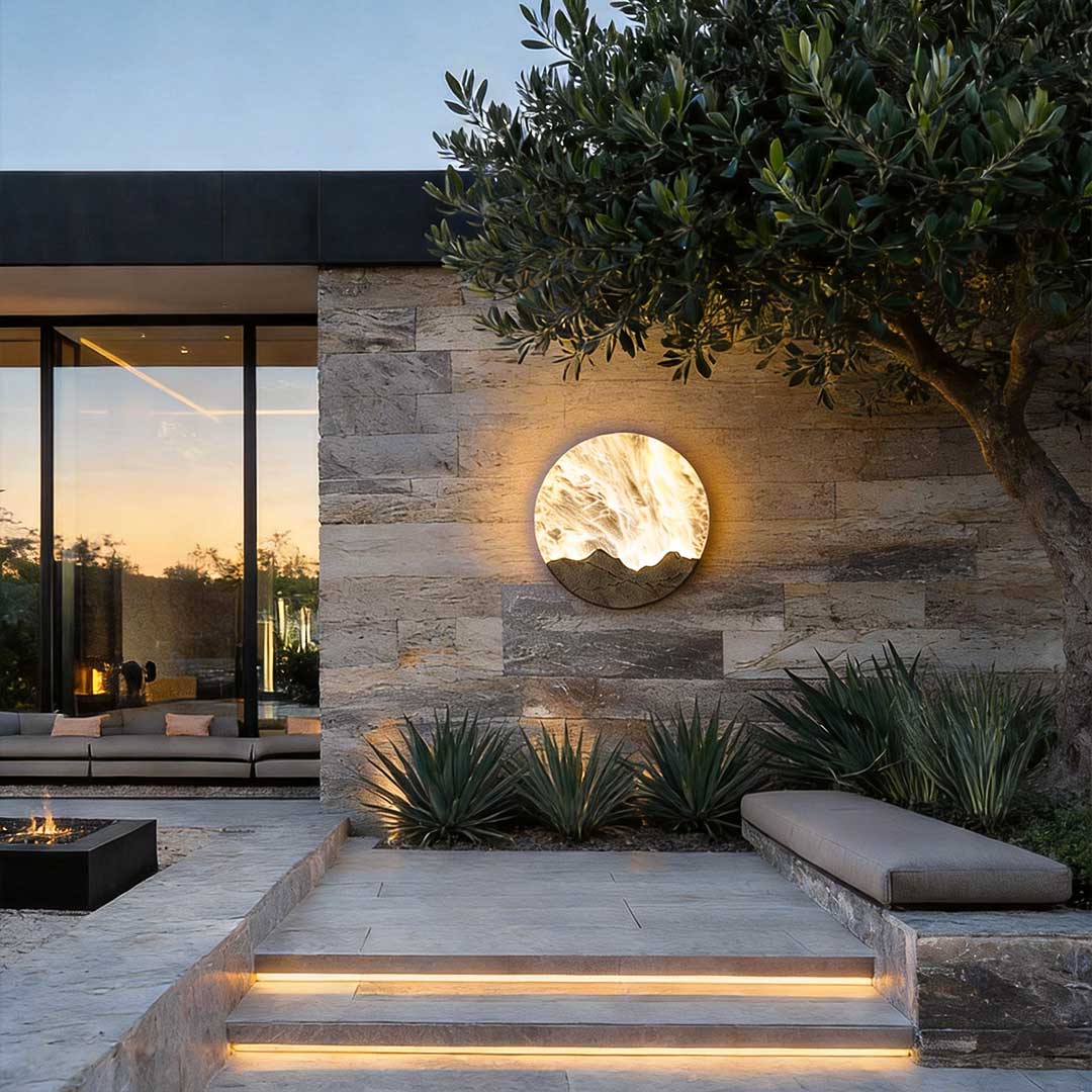 Round outdoor sconce casting a gentle glow on a modern house exterior at dusk.