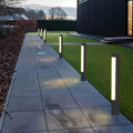Row of modern black square bollard lights lining a sleek gray stone pathway leading to a contemporary home.