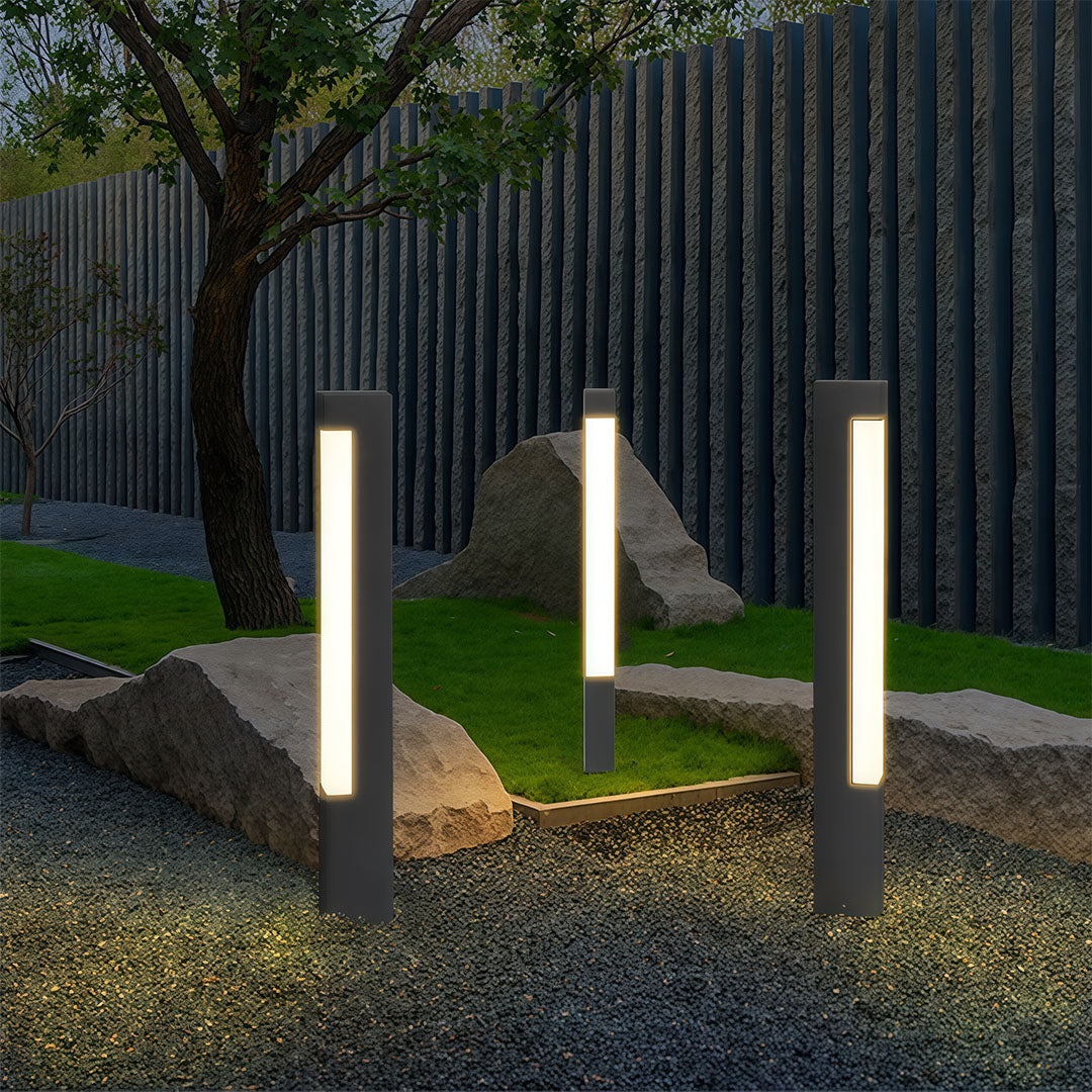 Set of square bollard lights placed in a rock garden border, providing bright, vertical light for evening safety.