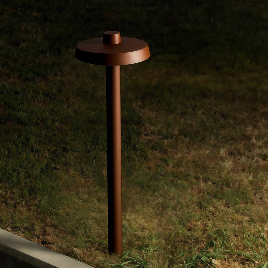 Silver aluminum path lights installed along a curved walkway, lighting up mulch and garden borders.
