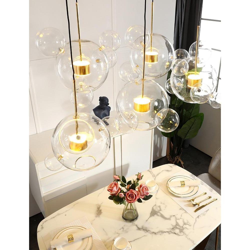 Single clear bubble chandelier suspended over minimal console table.