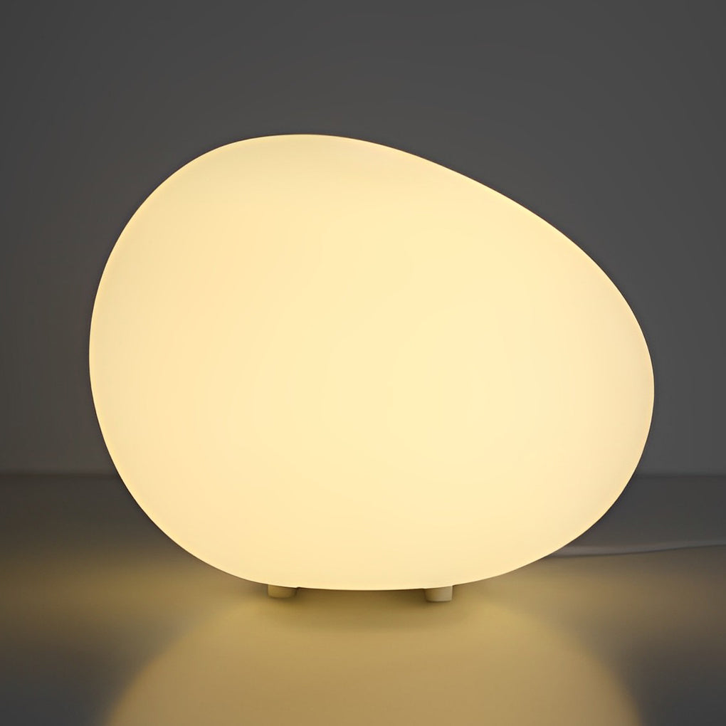 Single pebble light with warm glow on outdoor surface.