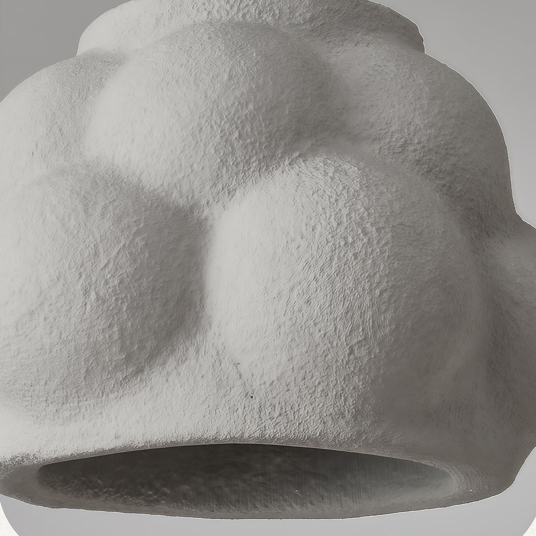 Close-up of single pendant light fixture showing bubble-like design and rough plaster surface.
