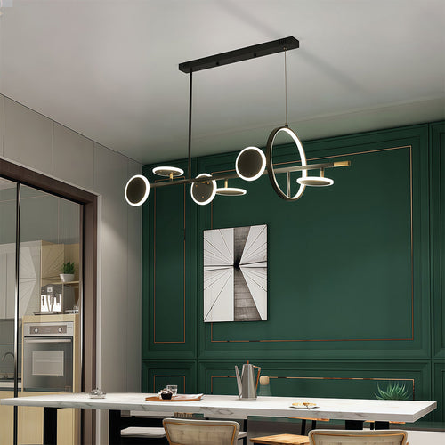 Sleek 6 light chandelier with black and gold accents, illuminating a dining area with a deep green accent wall.