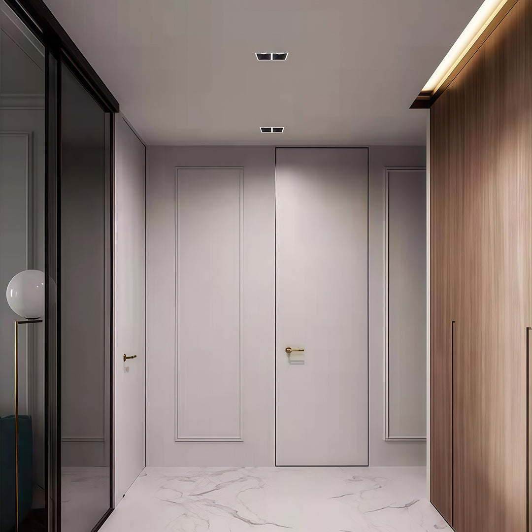 Sleek square LED downlights in a black finish, installed in a minimalist white hallway ceiling.