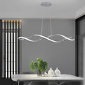 Waveform pendant light with sleek black design hanging above modern dining table and chairs.