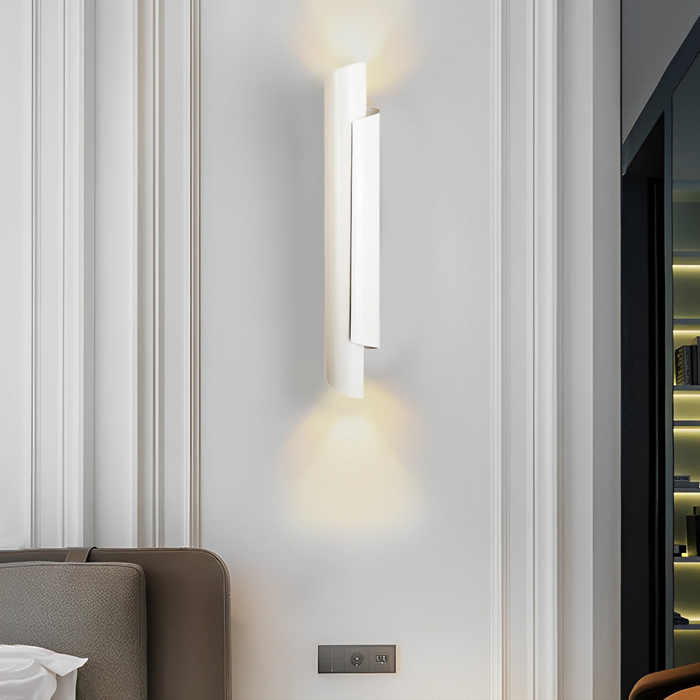 Sleek scroll wall sconce in white, providing soft light above a neatly made bed in a modern room.