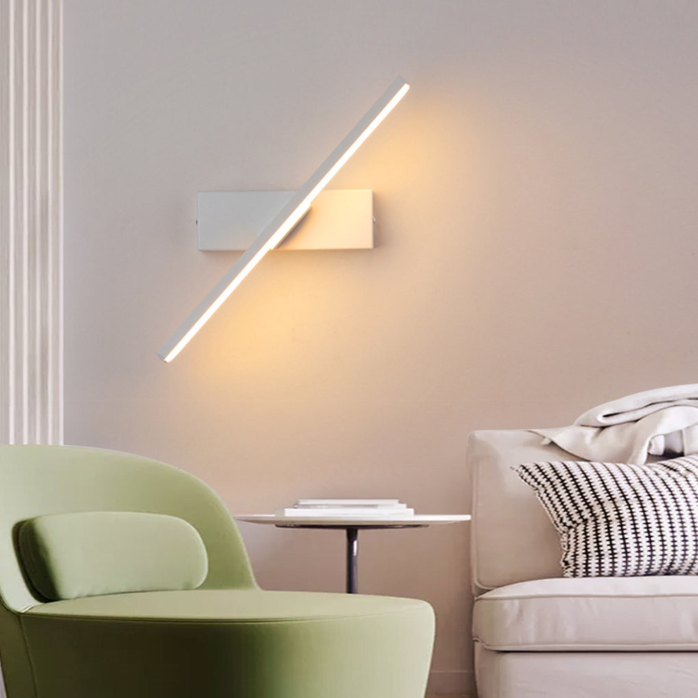 Sleek swivel wall light in white and black, casting warm light in a cozy living room with a green armchair.