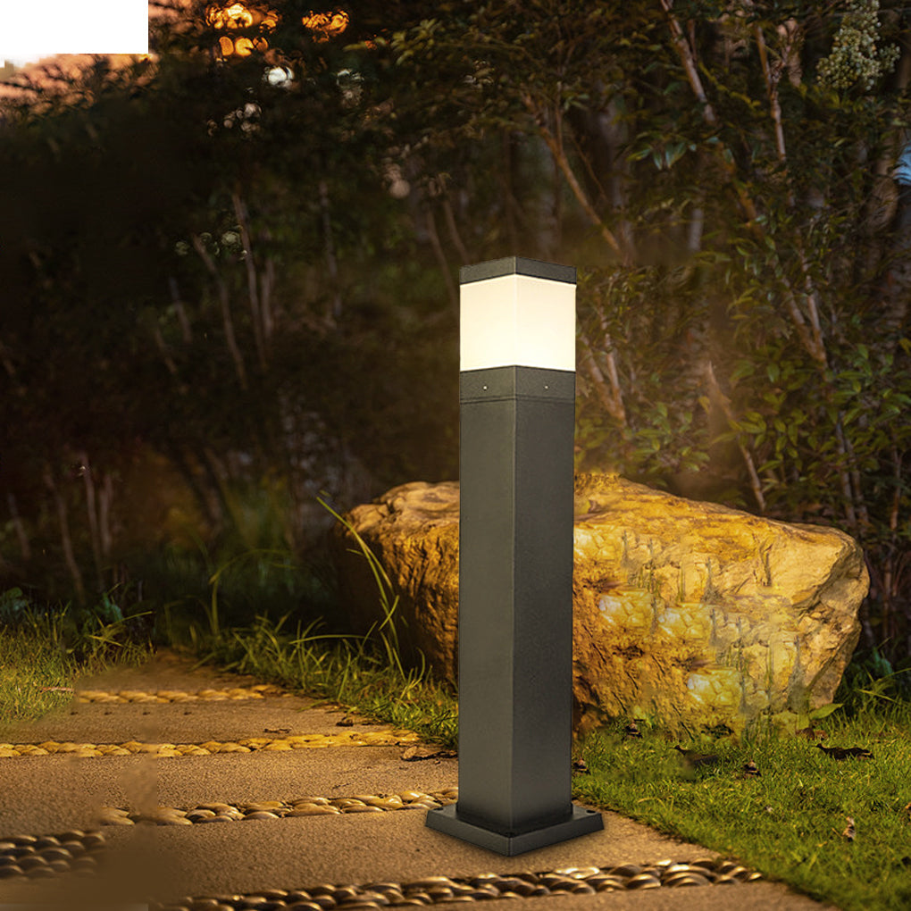 Slim black commercial bollard lights providing subtle illumination for a residential driveway and greenery.