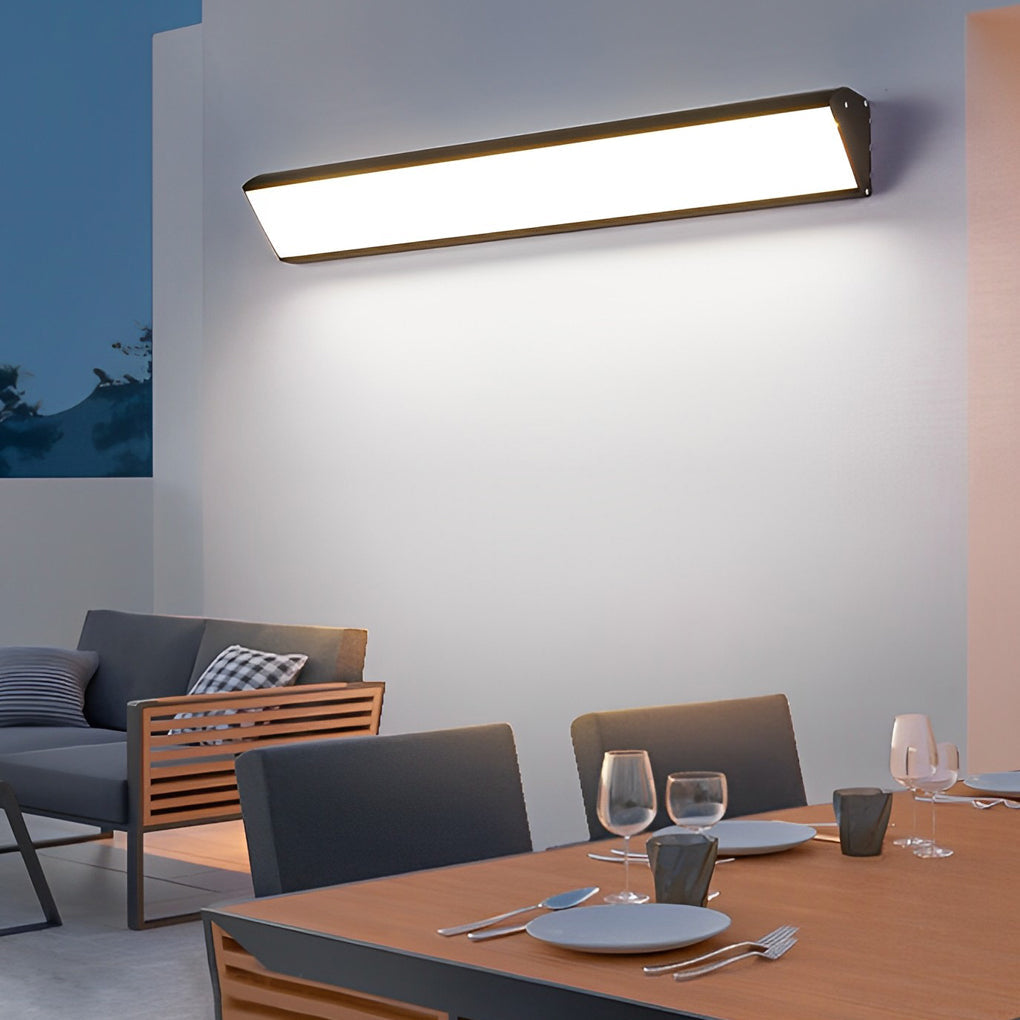 Slim linear outdoor wall sconce casting soft light across a modern terrace wall.