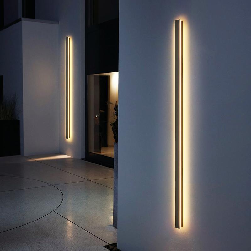 Slim long outdoor wall lights installed beside entrance, providing warm and contemporary vertical illumination.