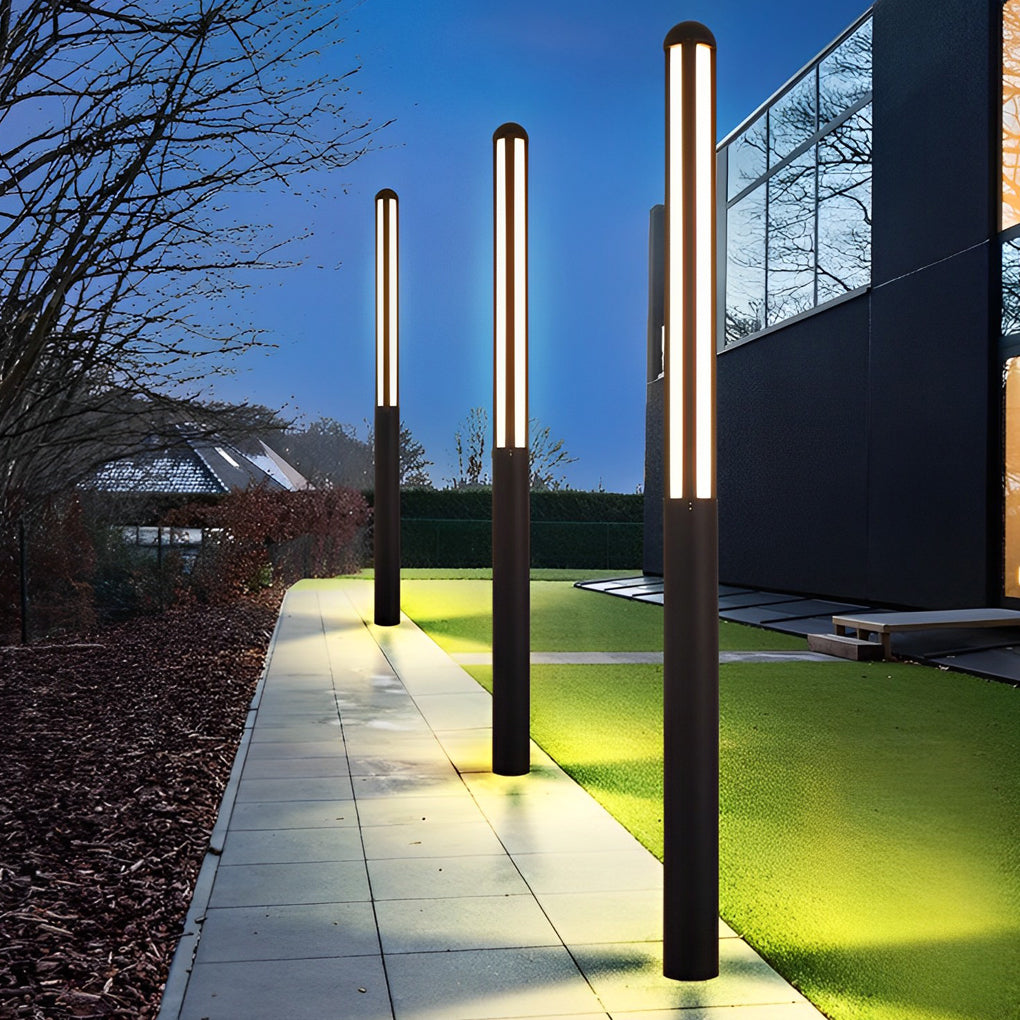 Tall garden bollard light casting soft light on garden pathway at dusk.