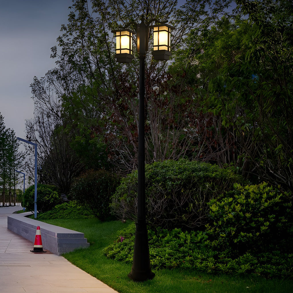 2 head outdoor post light casting soft light on paved walkway surrounded by trees.