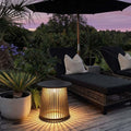 Solar coffee table with a woven design, providing warm illumination on a patio.