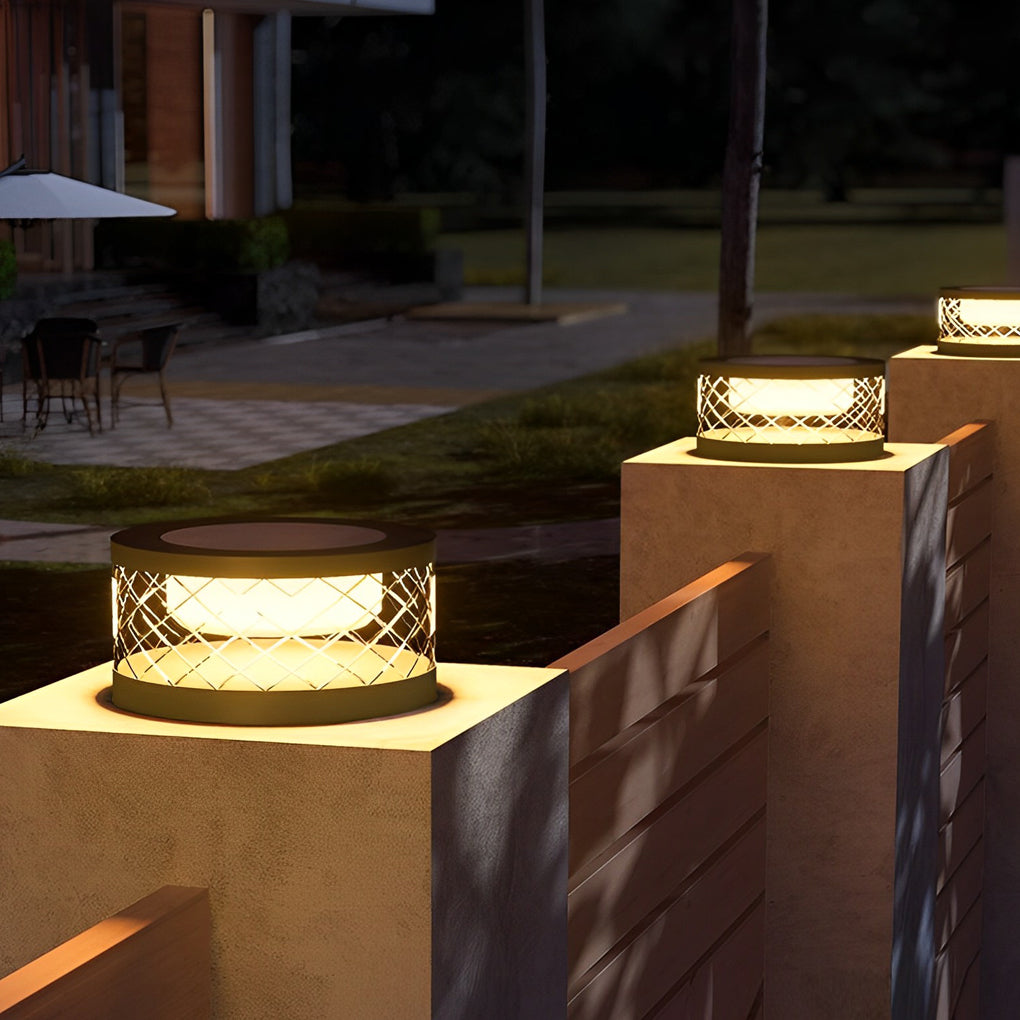 Solar cylinder pillar light with a black finish, providing ambient light near a patio.
