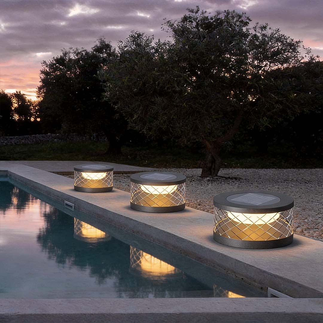 Solar cylinder pillar light with a sleek design, providing warm light along a garden path.