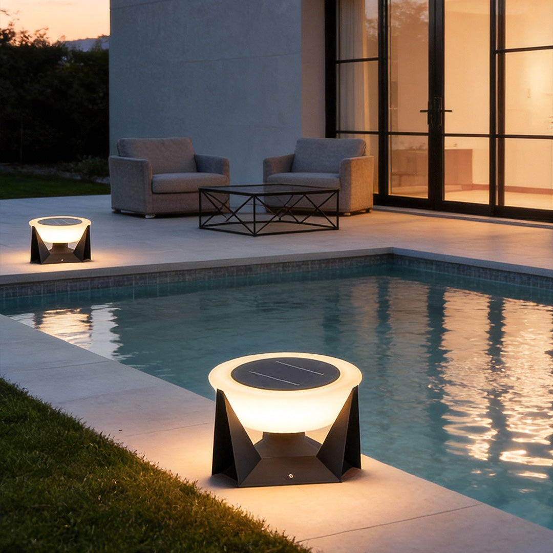 Solar fence pillar light placed beside a modern swimming pool, providing soft ambient lighting at night.
