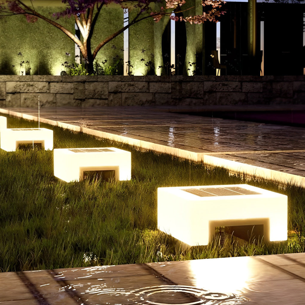 Low profile solar front lawn lights lining modern garden walkway at night.