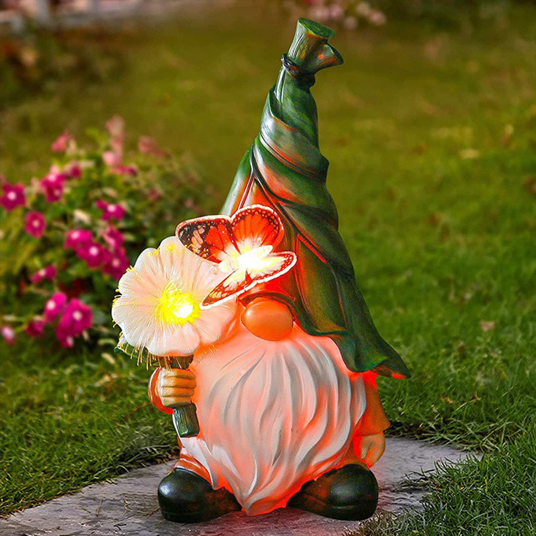 Solar gnomes garden lights illuminating a garden pathway with a gnome holding a flower.