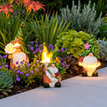 Solar gnomes garden lights adding whimsical charm to a flower bed with colorful blooms.