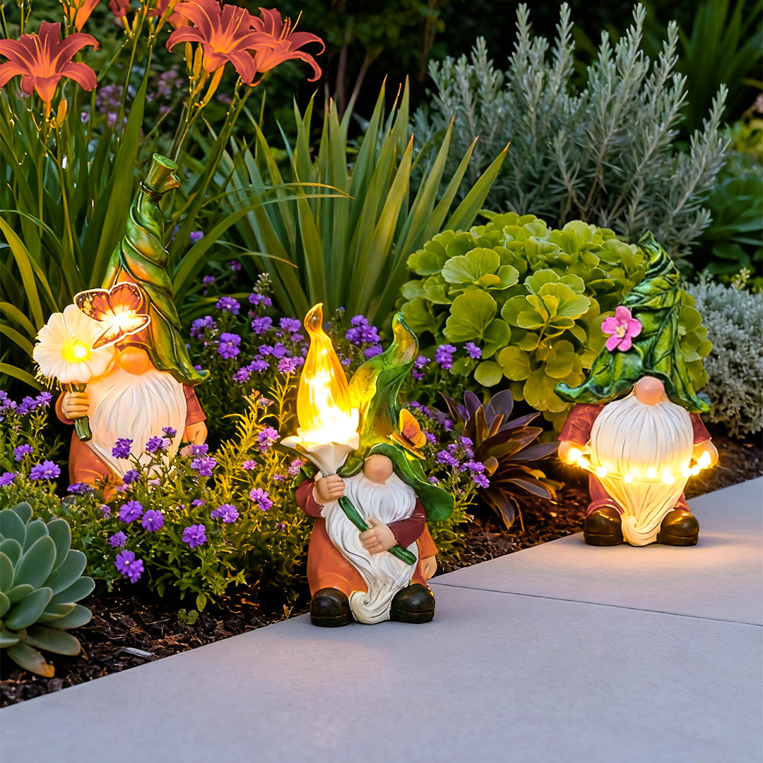 Solar gnomes garden lights adding whimsical charm to a flower bed with colorful blooms.