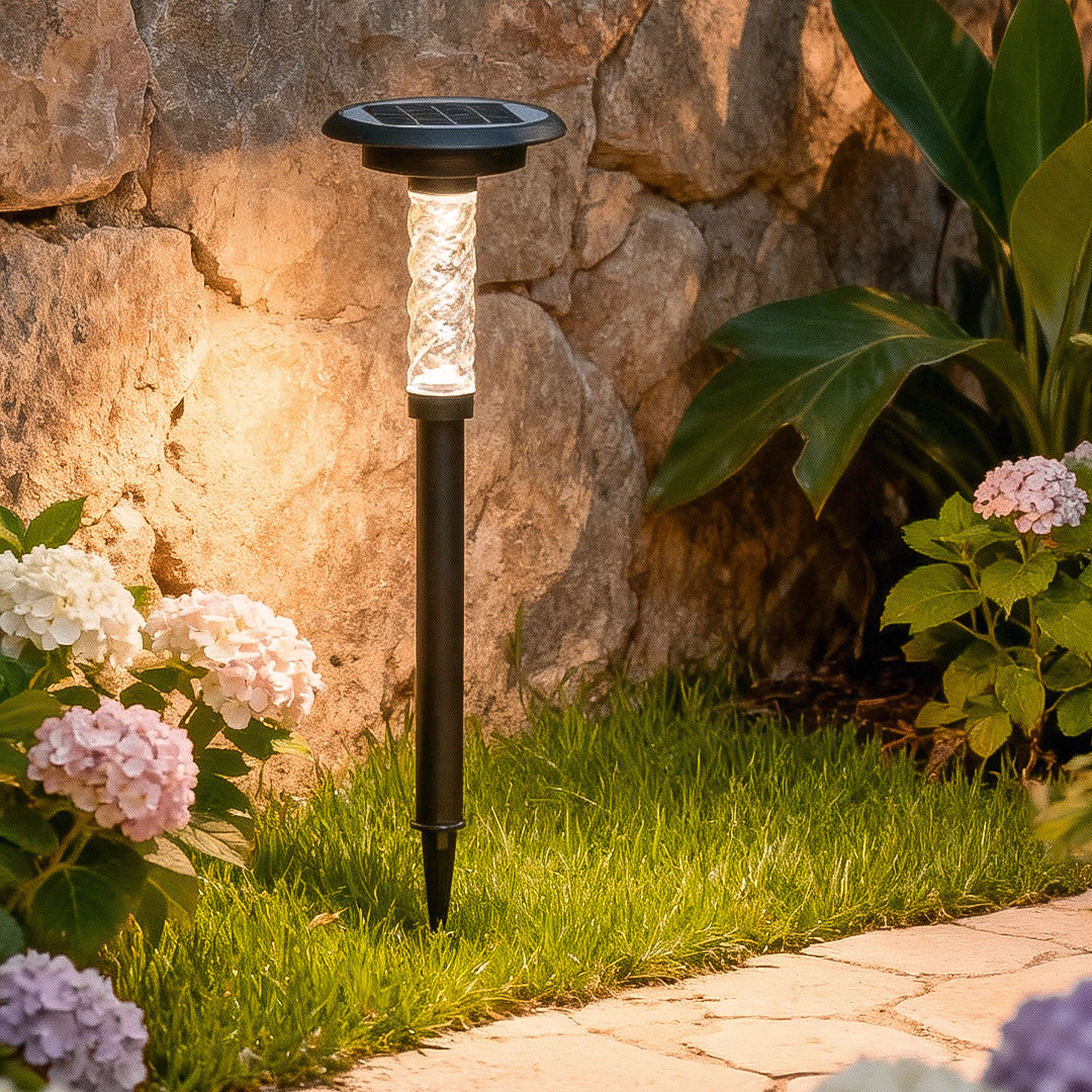 Solar outdoor path lighting installed along stone landscaping, casting warm illumination onto plants and walkway.