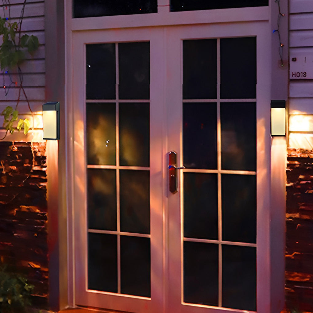 Solar powered outdoor sconces with black frame illuminating entrance door with glass panels.