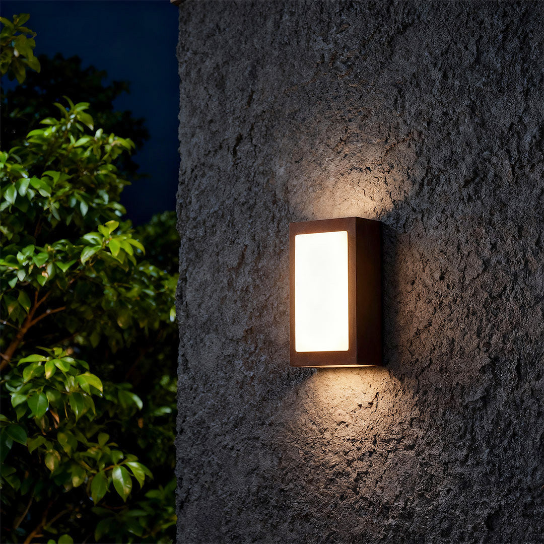Sophisticated black sconce wall lights featuring glass shade chandelier influence with up-down illumination on dark textured facade.