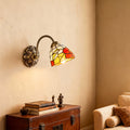 Sophisticated stained glass wall sconce lighting with glass shade chandelier influence providing accent lighting above storage chest.
