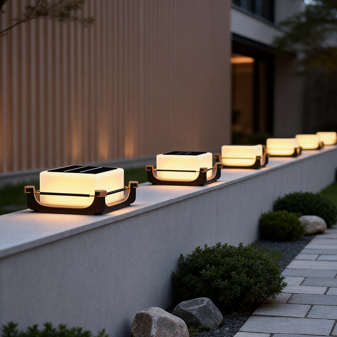 Square acrylic pier light aligned on low outdoor walls, highlighting architectural lines in a minimalist courtyard.