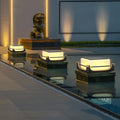Square acrylic pier light installed beside a modern outdoor pool, creating soft ambient pathway illumination at dusk.