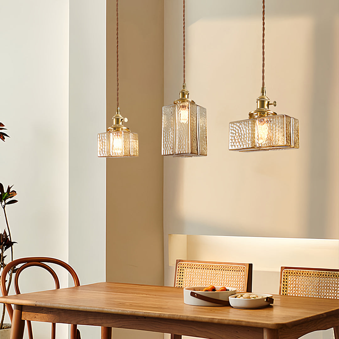Square glass pendant lights creating ambient lighting in modern dining room with blue accent wall and natural wood.