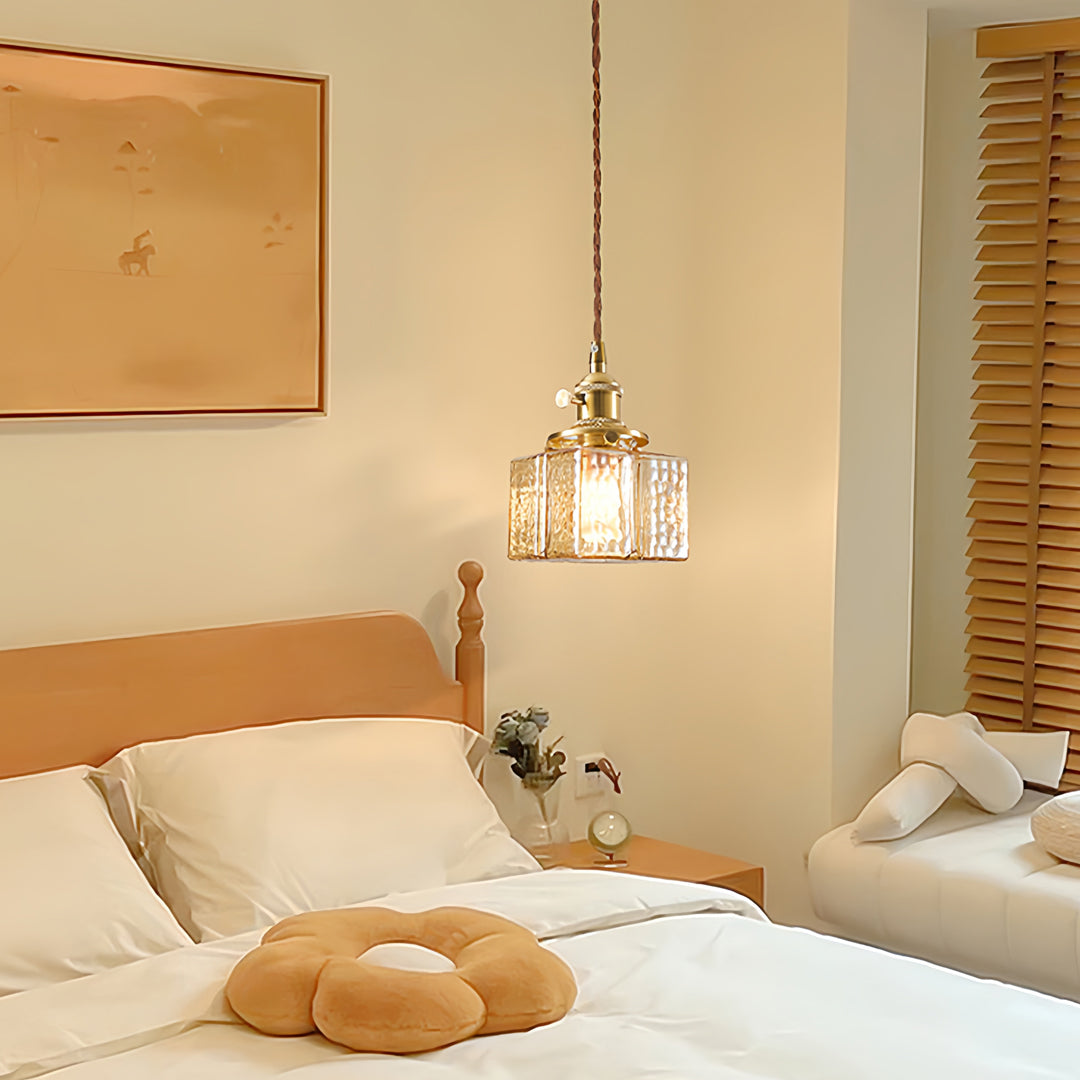 Square glass pendant lights in elegant bedroom with brass hardware providing warm ambient lighting beside natural wood.